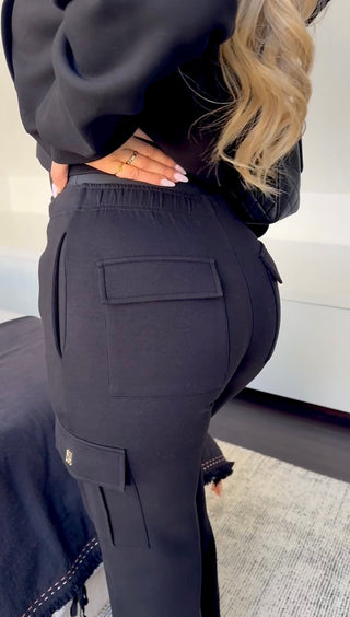 Side angle of the INTIMISSY Caviar Black Studio Plush Cargo pants highlighting cargo pockets and plush 360GSM fabric